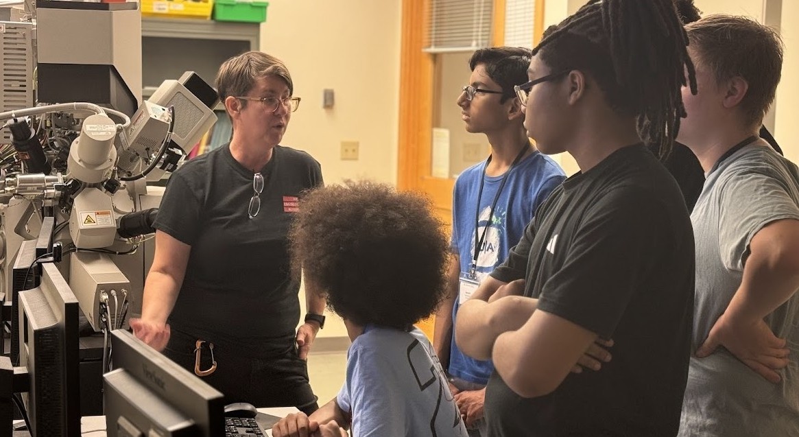 Students in a lab look at equipment with an instructor