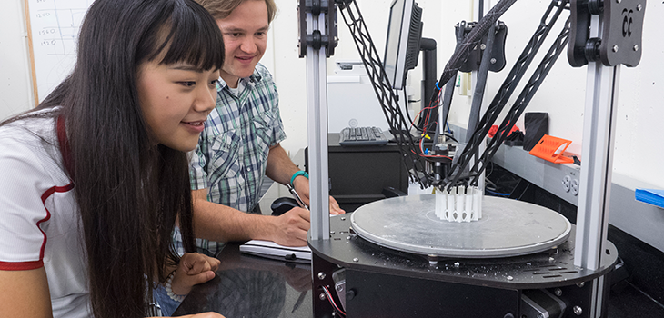 Two mechanical engineering students working on an item in a lab