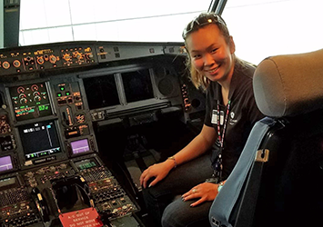 Alexis Conway, aerospace engineering class of 2019, pictured in the cockpit of an airplane, with lots of buttons lit up!