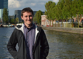 Dillon Staub, electrical engineering class of 2018, pictured in front of a river city front in Germany