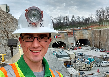 Joe Kaufman, civil engineering class of 2018, takes a selfie in glasses, a hardhat and safety vest while on a construction site.