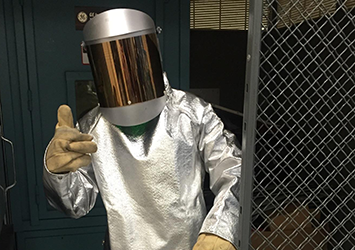 Joe Rayho, aerospace engineering class of 2018, in a silver foil protective suit wearing gloves and a large welding mask.