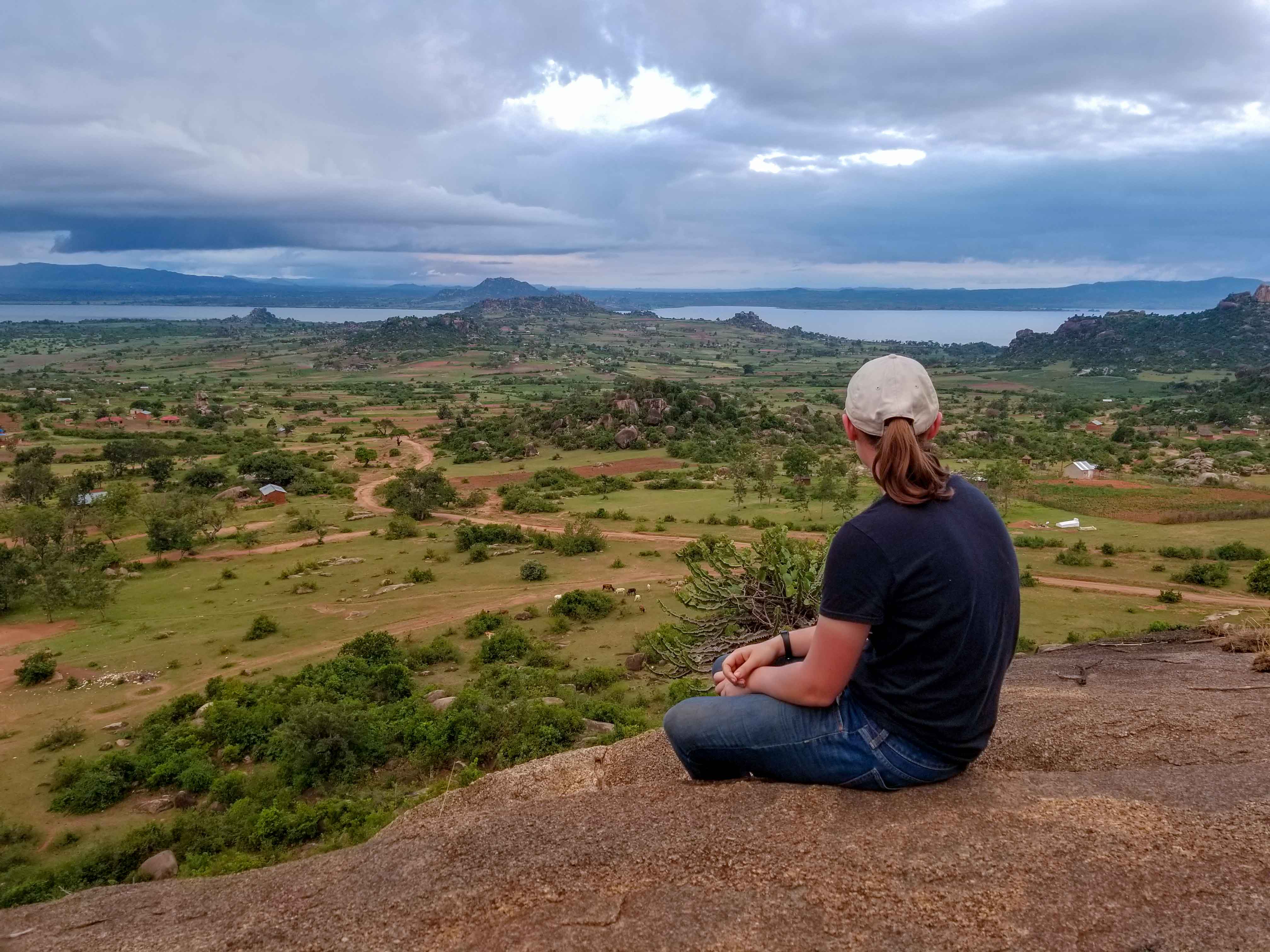 Student sitting on a mountain top overlooking the valley 