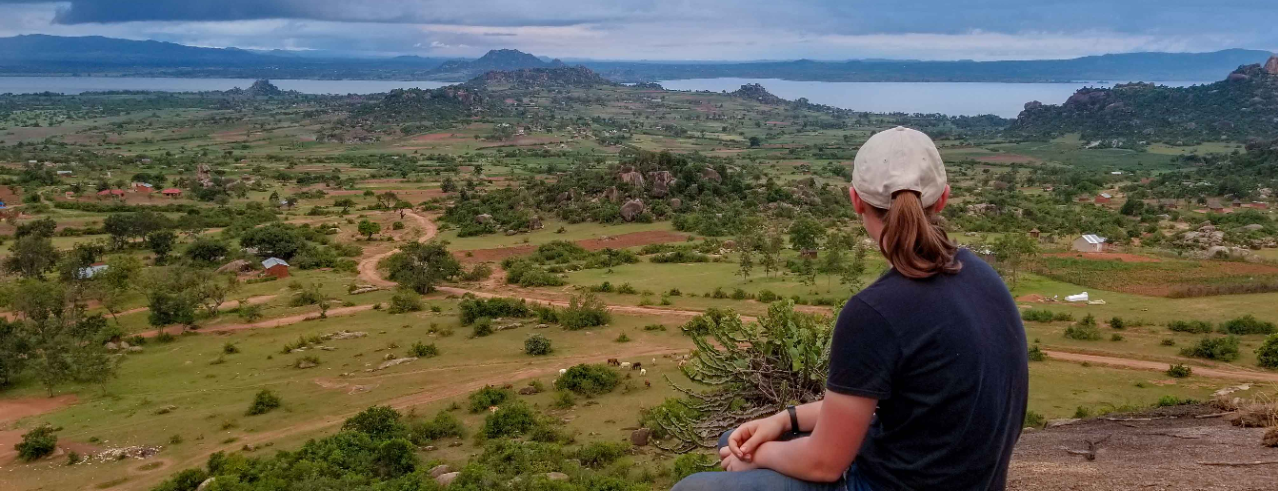 Student sitting on a mountain top overlooking the valley